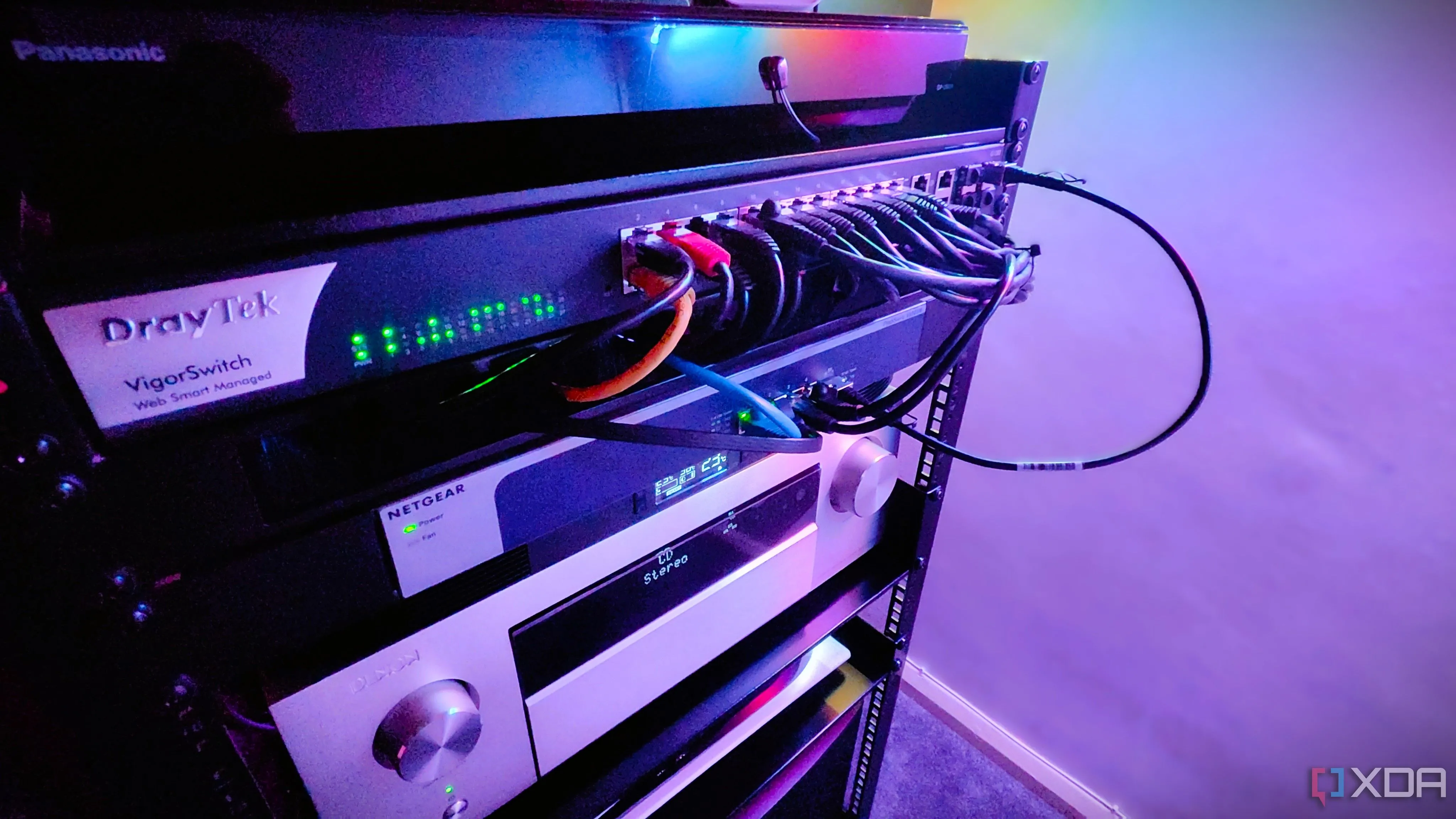 Cận cảnh một tủ rack mạng với nhiều switch và thiết bị AVR được kết nối, biểu thị sự phức tạp của hệ thống mạng cần được đơn giản hóa bằng VLAN Trunking.