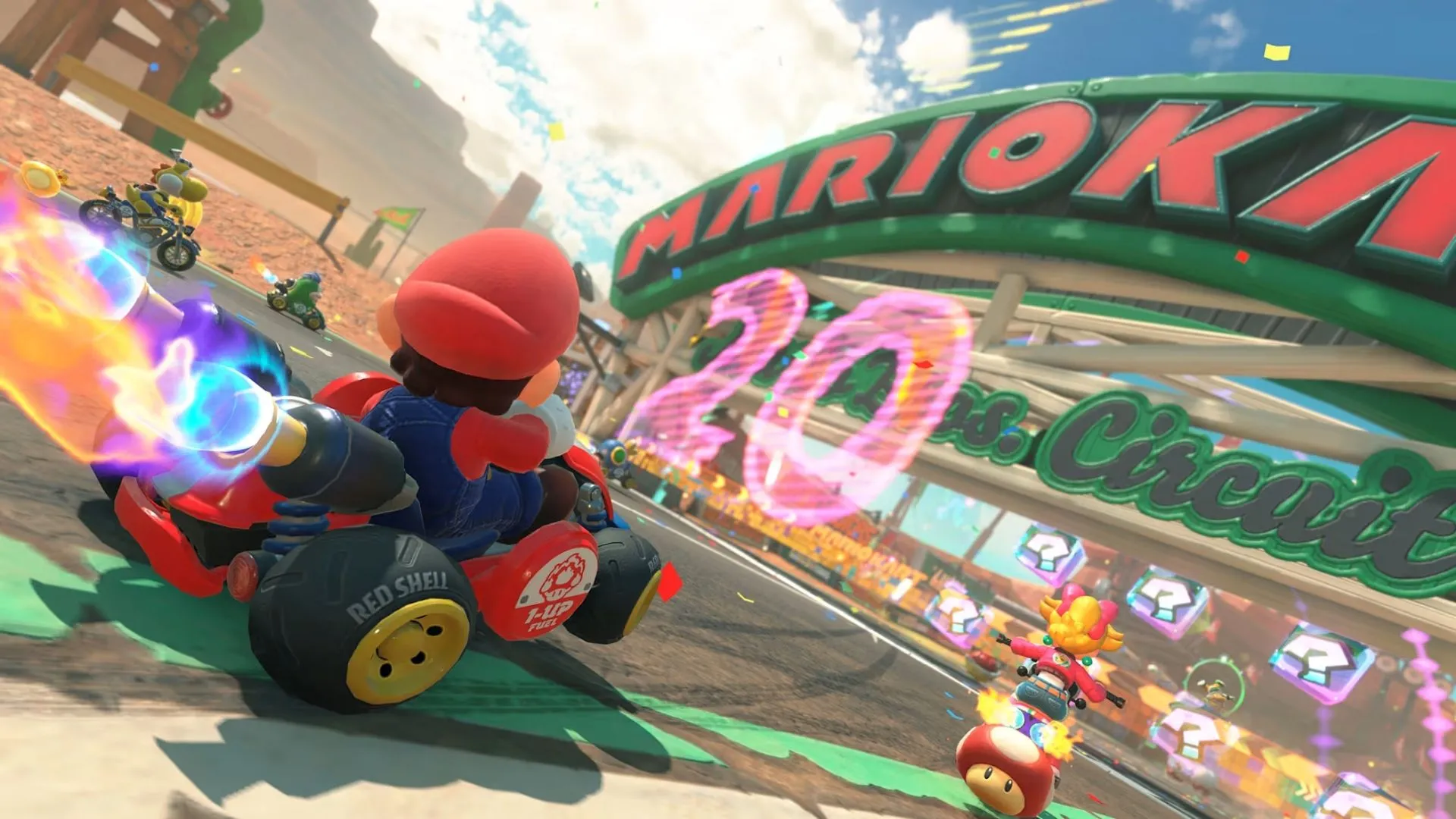Daisy và Donkey Kong đua trên đường Rainbow Road đầy màu sắc với lâu đài Bowser trong Mario Kart World.