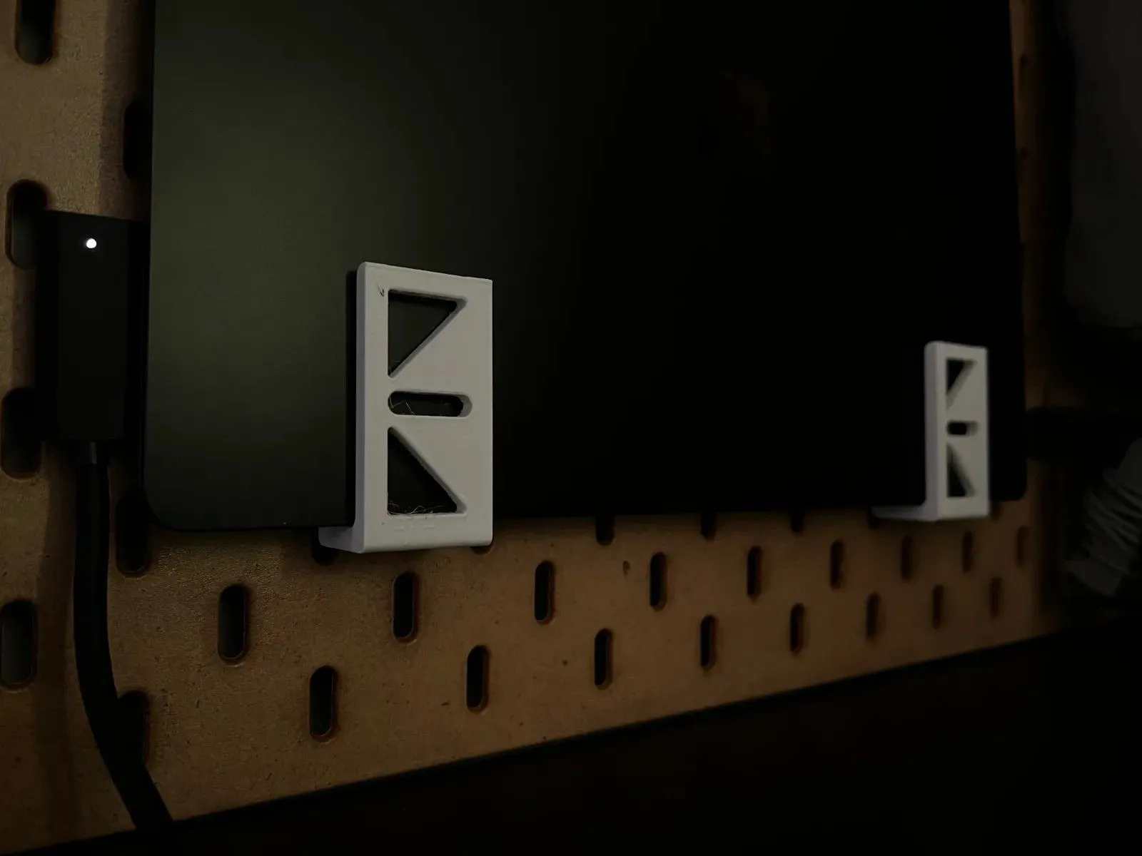 Giá đỡ laptop in 3D màu trắng gắn trên bảng pegboard IKEA Skadis, giúp tiết kiệm không gian bàn làm việc.