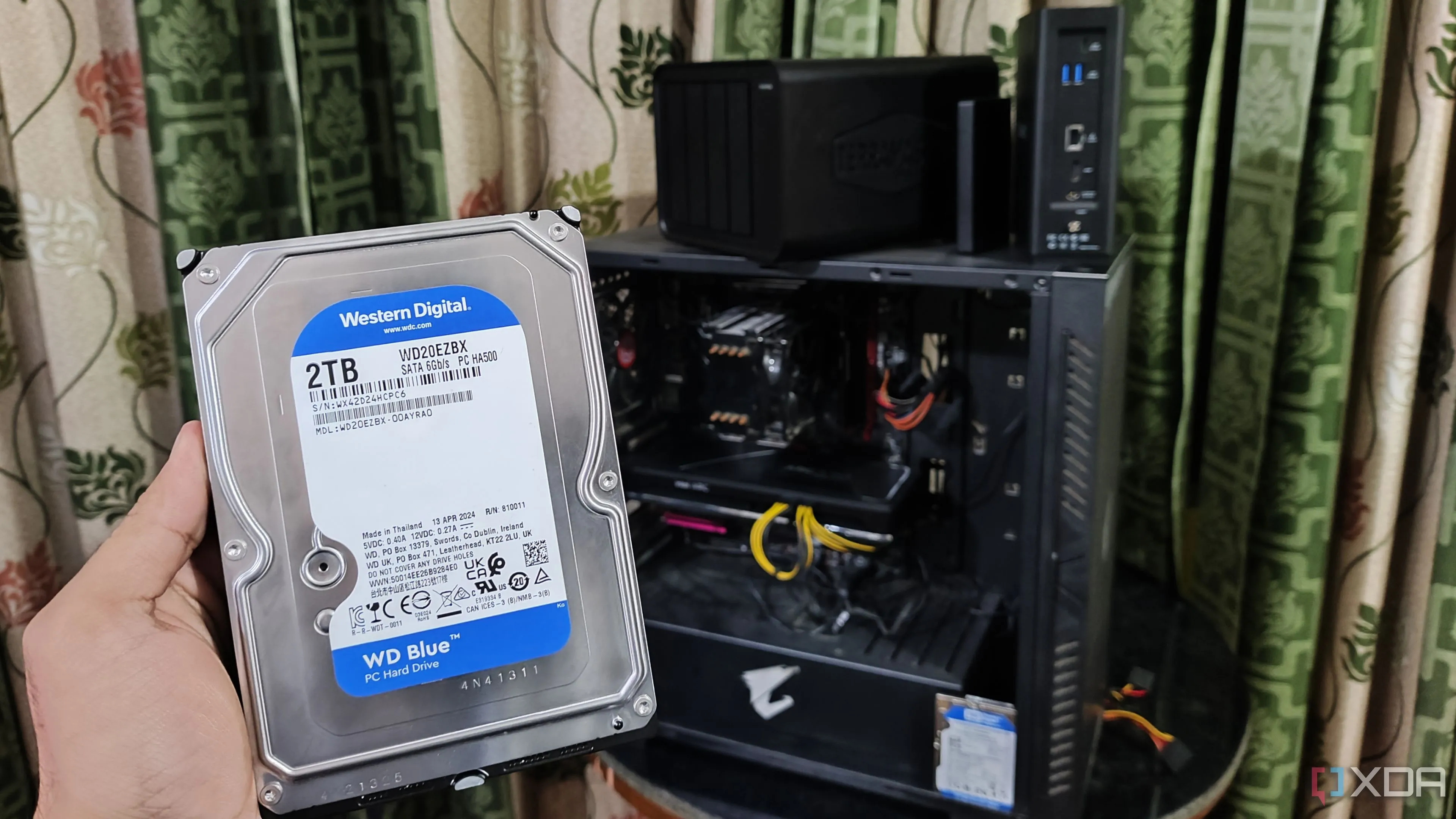 Một người cầm ổ cứng HDD trước máy tính và hai thiết bị NAS TerraMaster