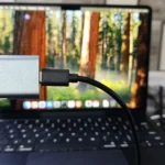 Người dùng đang cầm vỏ bọc NVMe SSD trước máy tính MacBook