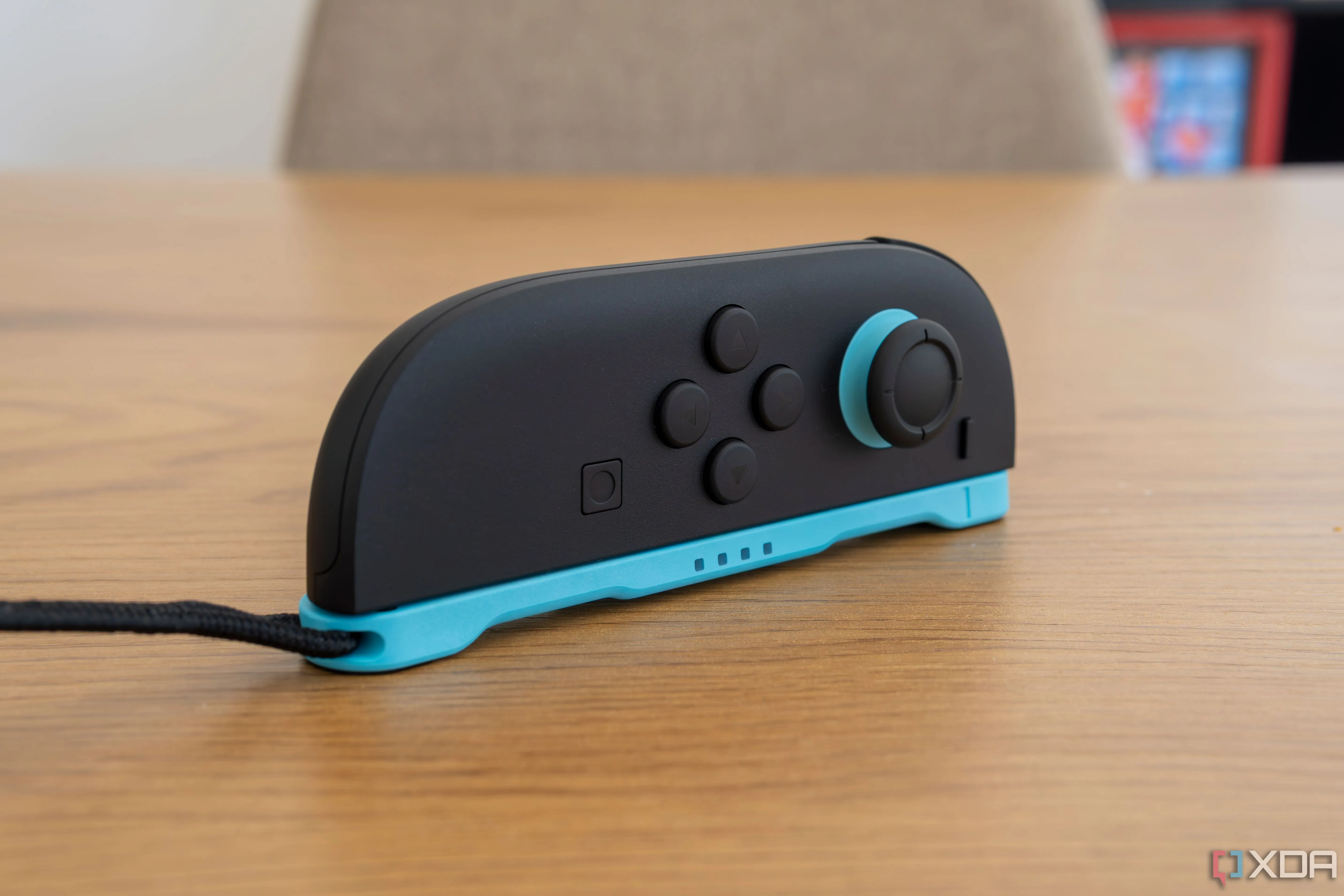 Tay cầm Joy-Con 2 đặt ngang, có gắn dây đeo, được dùng như một con chuột, minh họa khả năng cảm biến chuyển động của thiết bị