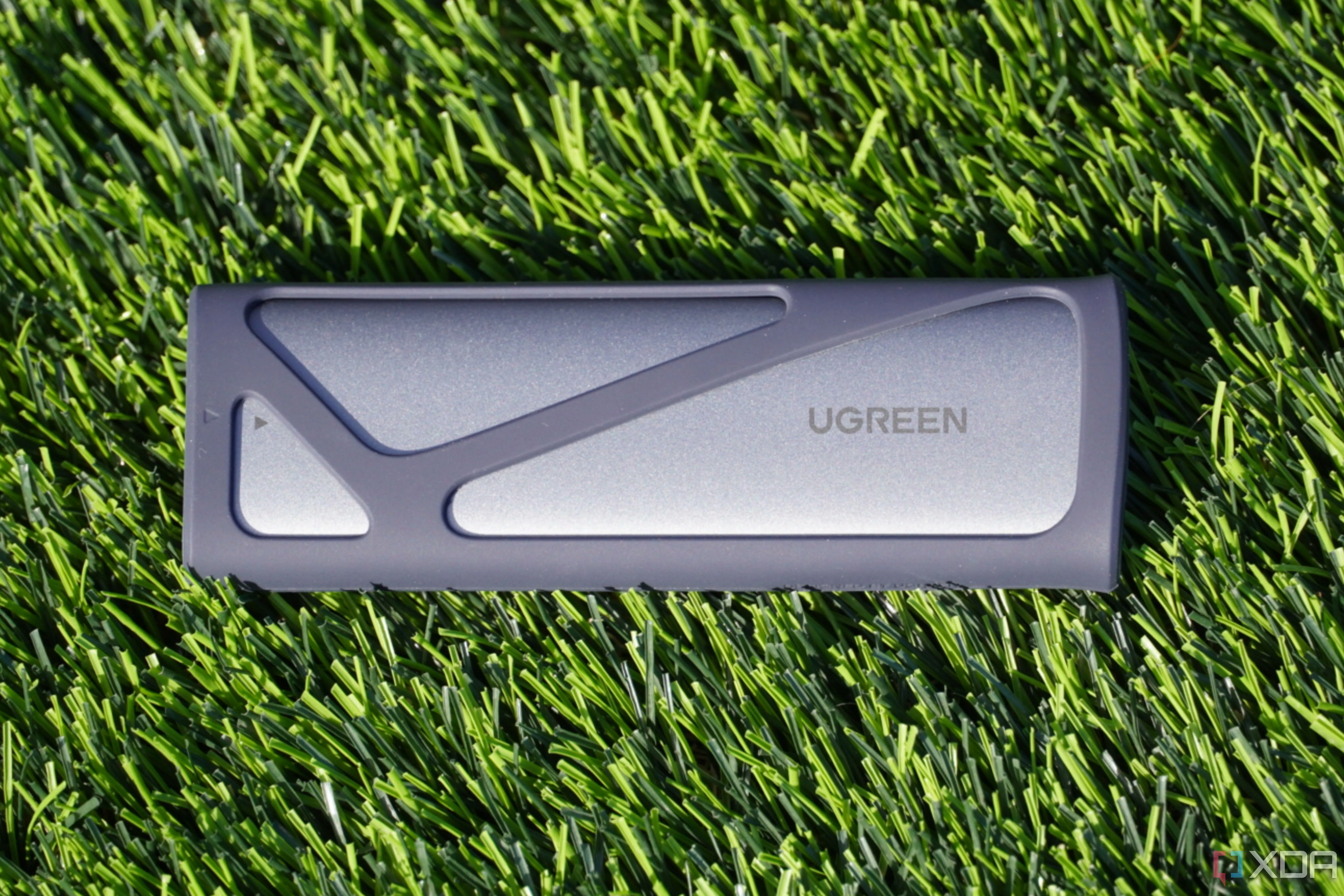 Vỏ bọc SSD Ugreen M.2 NVMe nằm trên nền cỏ, thể hiện thiết kế nhỏ gọn